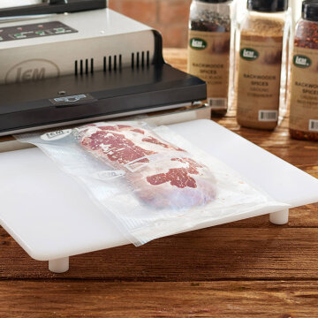 A piece of steak in a vacuum sealed bag on a wood table.