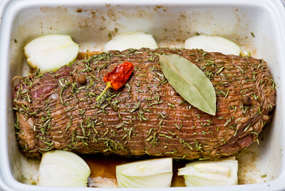 A seasoned roast in a pan on a layer of onions